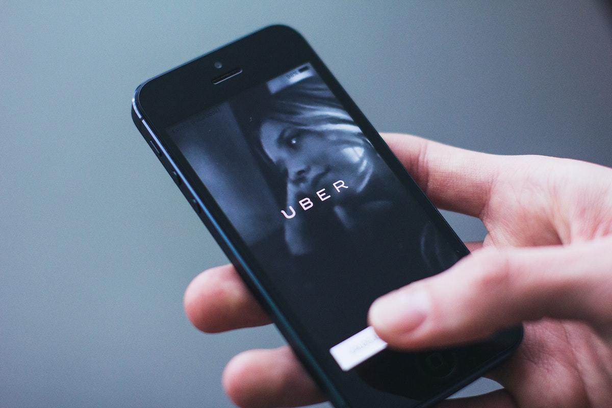 Pessoa segurando celular com tela desbloqueada para usar app e chamar Uber Driver