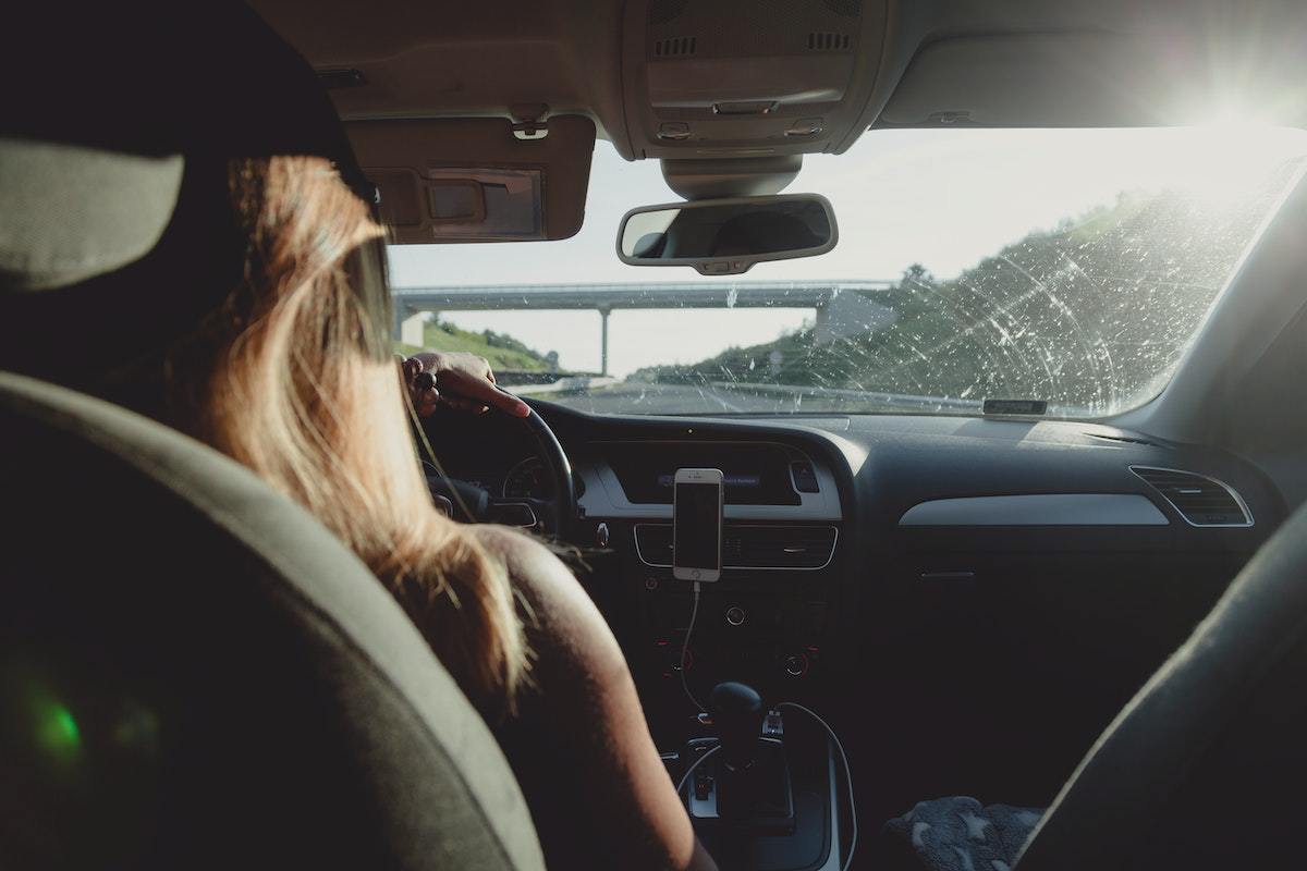 Uber Driver do sexo feminino dirigindo carro em foto tirada de trás, do banco de passageiros